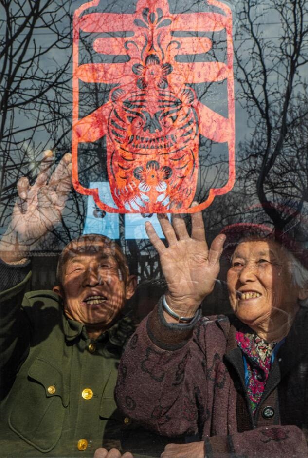 臘月里，霍州市師莊鄉(xiāng)馮南垣村村民師榮光(左)在災(zāi)后重建的新家里貼窗花。(霍州市委宣傳部供圖)