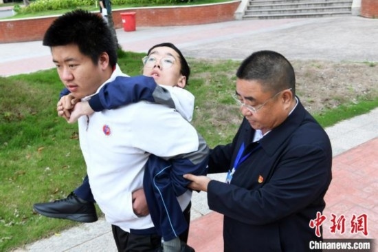 朱金祥背著鐘華強去教室上課的路上，也經(jīng)常碰到值班的校領(lǐng)導和老師前來搭把手。 卓忠偉 攝