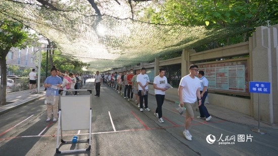 6月7日，烏魯木齊市第七十中學(xué)門(mén)口，考生們有序進(jìn)入考場(chǎng)。人民網(wǎng) 李欣洋攝