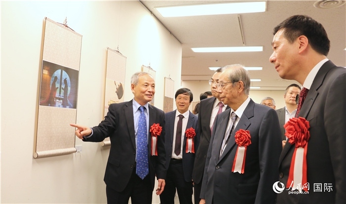 “湖州印象”攝影展主創(chuàng)、世界華人攝影協(xié)會(huì)副會(huì)長馮學(xué)敏向吳江浩大使、福田康夫前首相等嘉賓介紹展出作品。（人民網(wǎng) 許可攝）