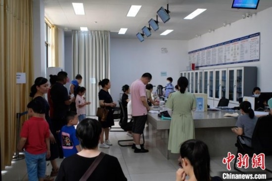 圖為在戶籍辦證廳內(nèi)排隊等待的家長和孩子。劉俊聰 攝