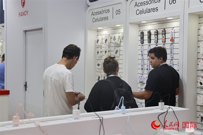 幾名參觀者在一個(gè)展臺(tái)前了解手機(jī)配件。（人民網(wǎng)記者 時(shí)元皓攝）