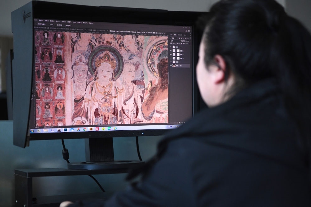敦煌研究院文物數(shù)字化保護團隊圖像處理人員年海麗在拼接壁畫圖像（2023年4月25日攝）。數(shù)字化探索為莫高窟的保護與傳承開辟了全新路徑，數(shù)字技術(shù)讓敦煌文物走出洞窟，跨出國門，走向“永久保存、永續(xù)利用”。新華社記者 陳斌 攝
