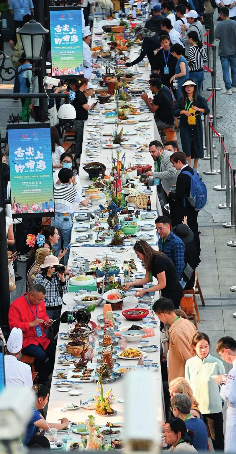 市民和游客在寧波舉辦的第三屆中國(guó)—中東歐國(guó)家博覽會(huì)暨國(guó)際消費(fèi)品博覽會(huì)上品嘗融合中國(guó)和中東歐美食的長(zhǎng)桌宴（2023年5月15日攝）。黃宗治攝/本刊