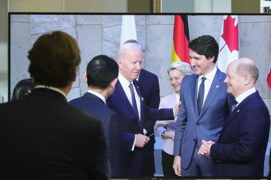 2022年3月24日，在比利時(shí)布魯塞爾的北約總部，一名男子觀看屏幕上美國總統(tǒng)拜登（右四）、歐盟委員會(huì)主席馮德萊恩（右三）、加拿大總理特魯多（右二）、德國總理朔爾茨（右一）出席七國集團(tuán)峰會(huì)合影儀式的畫面。新華社記者鄭煥松攝