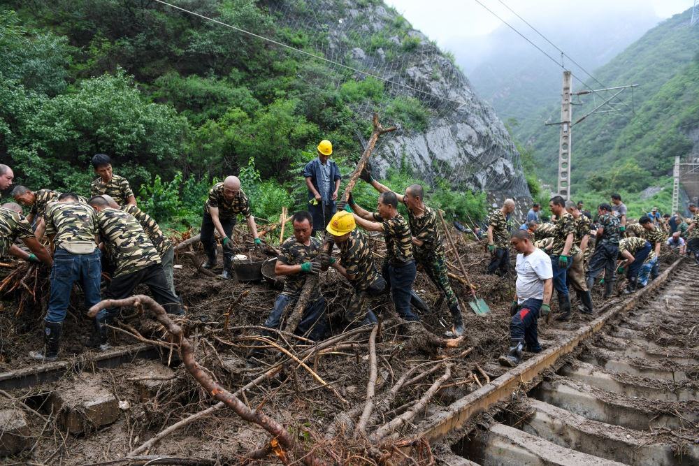 8月1日，在北京市門頭溝區(qū)水峪嘴村附近一段被阻斷的鐵路線上，中鐵六局工作人員在清理軌道上的雜物，全力恢復(fù)交通。新華社記者 鞠煥宗 攝