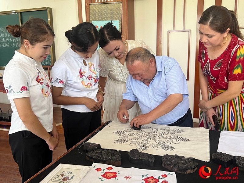 國家級非物質(zhì)文化遺產(chǎn)模戳印花布技藝傳承人吾吉阿西木?吾舒爾展示模戳印花布的制作過程。人民網(wǎng)記者 常雪梅攝