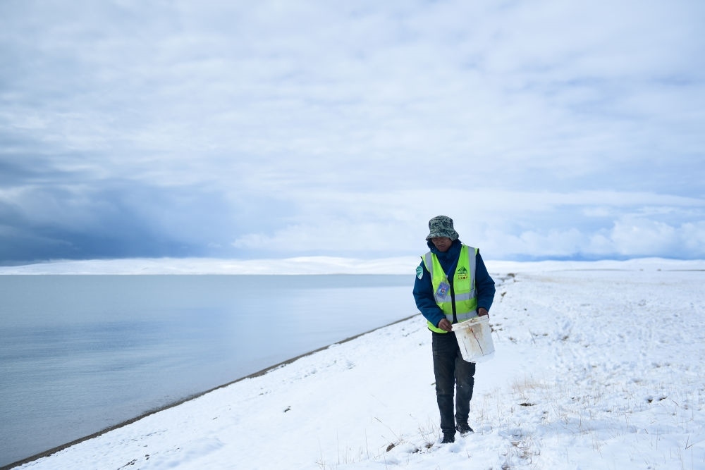 2021年10月20日，在青海省果洛藏族自治州瑪多縣扎陵湖鄉(xiāng)勒那村，三江源國家公園黃河源園區(qū)生態(tài)管護員在扎陵湖邊撿拾垃圾。新華社記者 張龍 攝