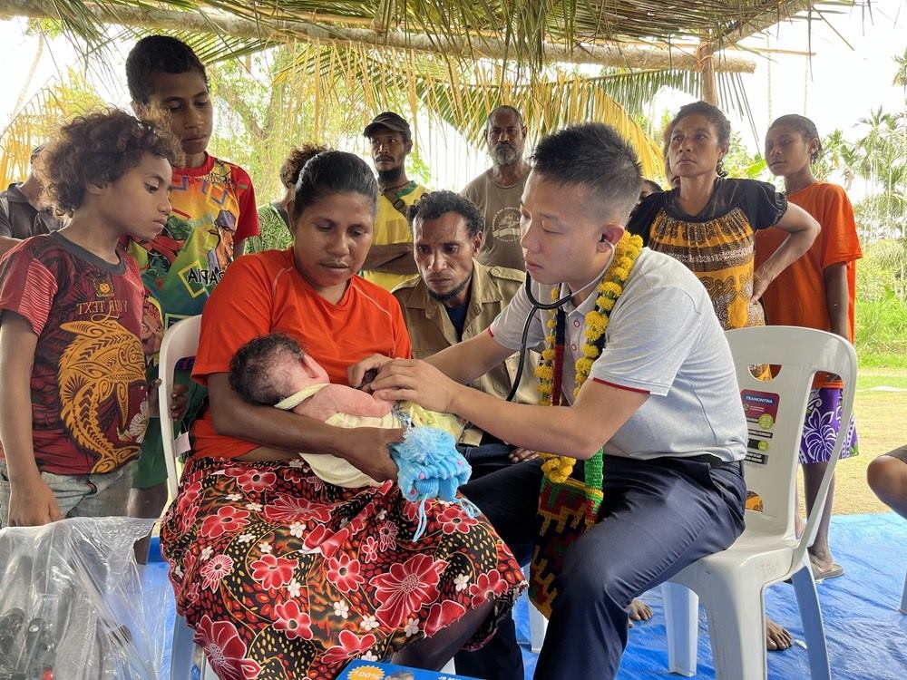 2023年8月5日，在巴布亞新幾內(nèi)亞中央省的一個(gè)村莊里，第12批援巴新中國(guó)醫(yī)療隊(duì)副隊(duì)長(zhǎng)、新生兒科副主任醫(yī)師劉振球?yàn)楫?dāng)?shù)貗雰郝?tīng)診檢查。新華社發(fā)（第12批援巴新中國(guó)醫(yī)療隊(duì)供圖）