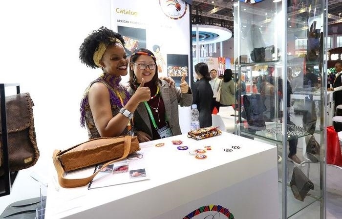 11月6日，一位參觀者（右）在第六屆進(jìn)博會國家展南非展臺試戴傳統(tǒng)首飾。