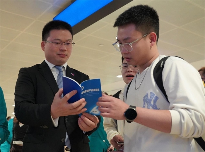 工作人員（左一）在發(fā)放《中國(guó)領(lǐng)事保護(hù)與協(xié)助指南》。 中國(guó)駐迪拜總領(lǐng)事館供圖