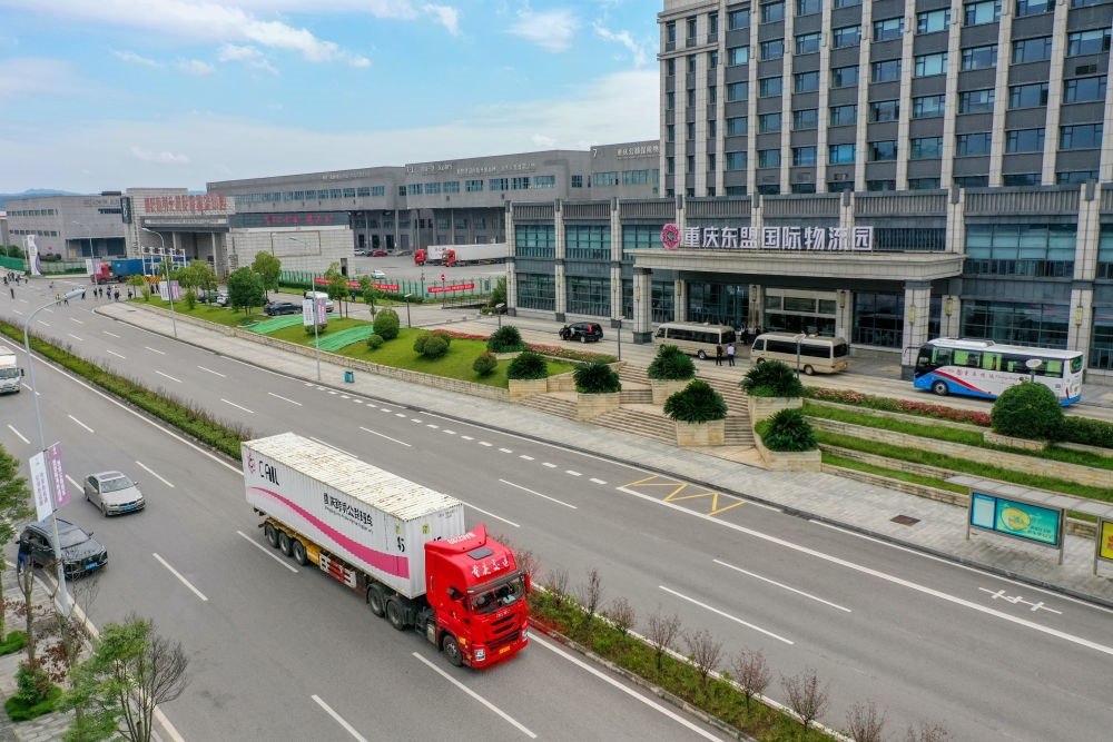 2023年10月11日，滿載筆記本電腦配件、發(fā)電機(jī)組件等產(chǎn)品的西部陸海新通道跨境公路班車從重慶南彭公路保稅物流中心駛出，將途經(jīng)廣西憑祥，直達(dá)越南（無人機(jī)照片）。新華社記者 黃偉 攝