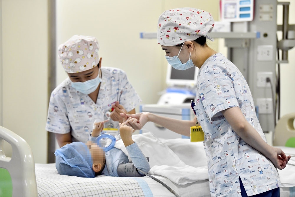 在山東省棗莊市婦幼保健院兒童ICU病房，醫(yī)護人員為完成靶向治療藥物諾西那生鈉的4歲脊髓性肌萎縮癥患兒加油鼓勁（2022年1月1日攝）。諾西那生鈉注射液是我國首個獲批治療脊髓性肌萎縮癥的進口藥物，2019年進入中國市場時，每針價格近70萬元。在2021年國家醫(yī)保目錄藥品談判中，以3.3萬元每針的價格進入新版醫(yī)保藥品目錄。新華社記者 郭緒雷 攝