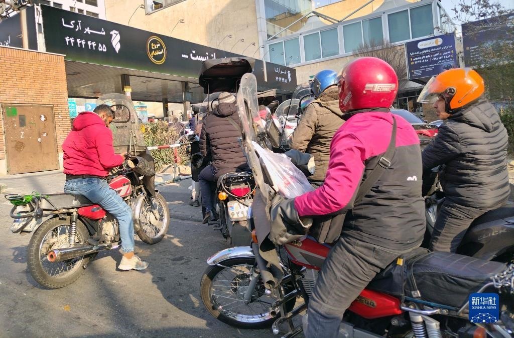 12月18日，摩托車在伊朗首都德黑蘭的一家加油站外等待加油。新華社記者 沙達提 攝