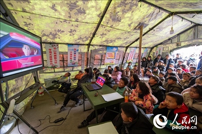 12月22日，在積石山縣大河家鎮(zhèn)大河村安置點(diǎn)，陸軍76集團(tuán)軍某旅搭建的“臨時(shí)學(xué)?！眱?nèi)，小朋友正在看動(dòng)畫片。人民網(wǎng)記者 翁奇羽攝