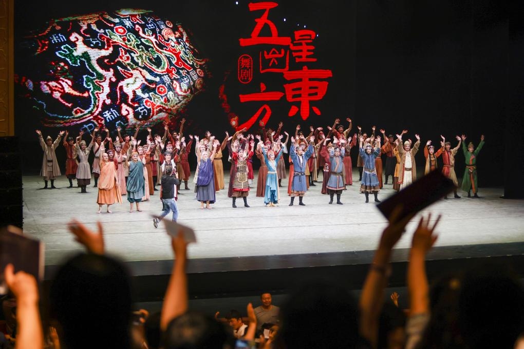 2023年7月31日，新疆和田地區(qū)新玉歌舞團(tuán)在烏魯木齊京劇院演出舞劇《五星出東方》后和觀眾互相揮手致意。這場演出是第六屆中國新疆國際民族舞蹈節(jié)的參演劇目之一，曾榮獲國家“文華獎(jiǎng)”等。新華社記者 郝昭 攝