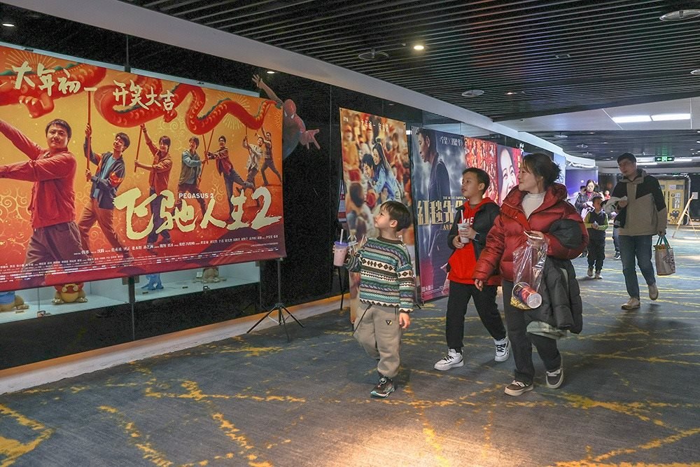 △ 2024年2月16日，在江西贛州一家電影院，觀眾從春節(jié)檔電影的宣傳展板前走過。