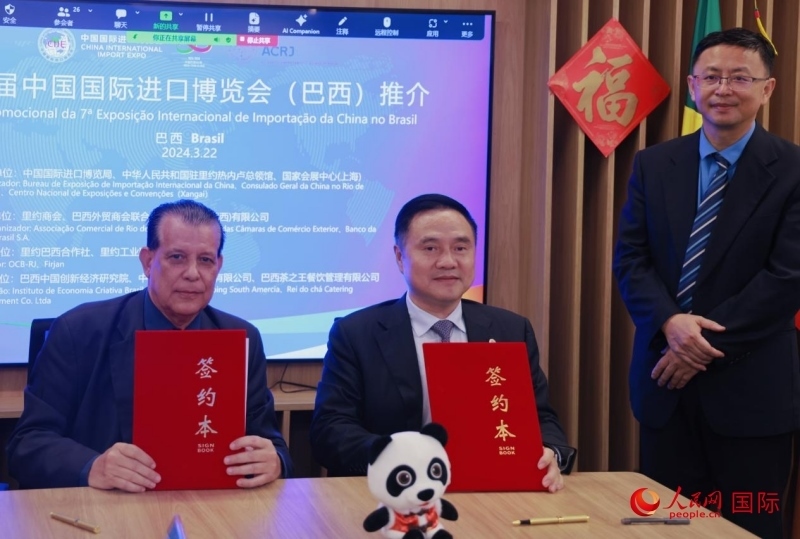 巴西外貿(mào)商會聯(lián)合會會長阿代爾·羅伯托（左）與中國國際進口博覽局副局長吳政平（中）現(xiàn)場簽訂協(xié)議。人民網(wǎng)記者 宋亦然攝