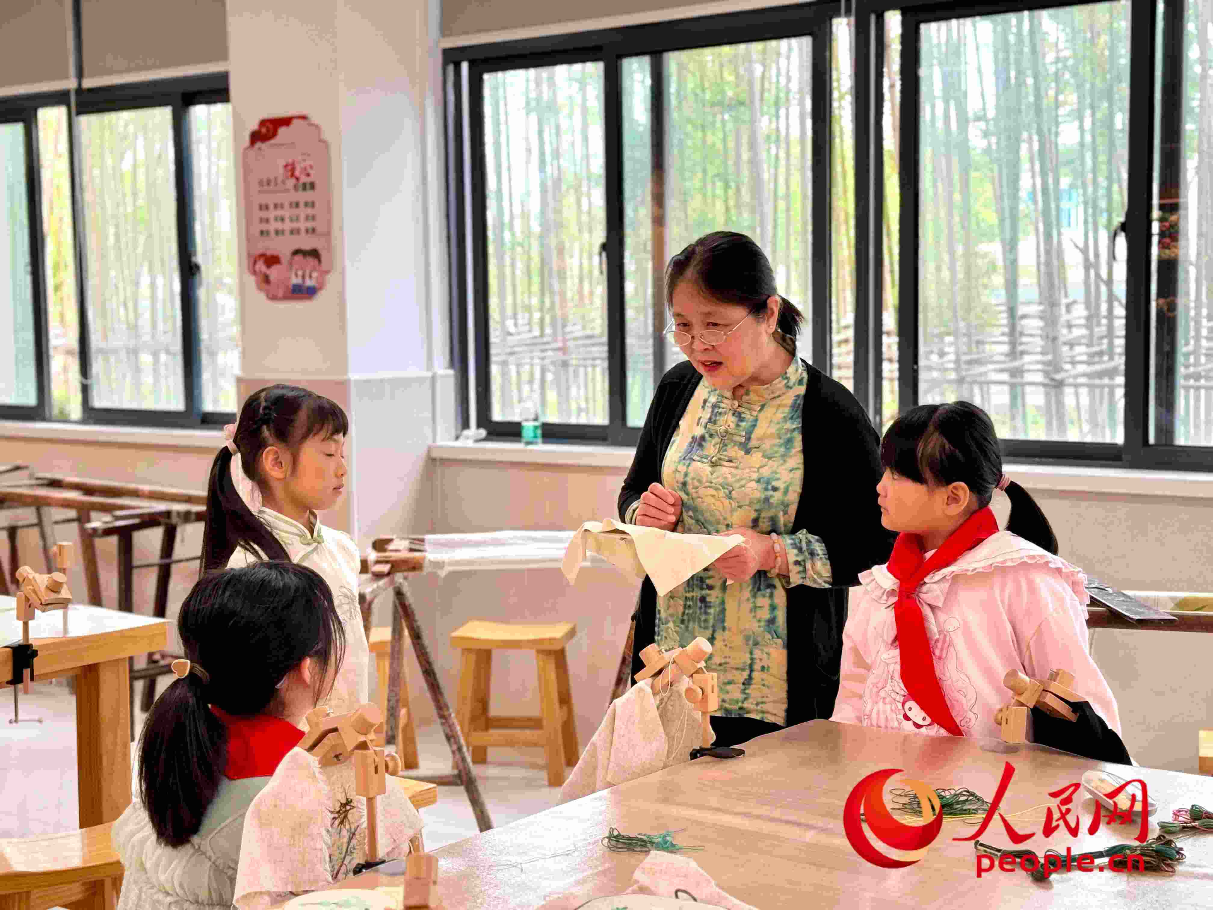 顧建珍（左三）在教孩子們刺繡知識(shí)。人民網(wǎng) 周靜圓攝