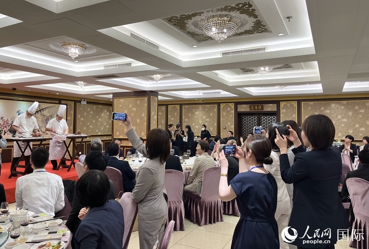 國家級(jí)非物質(zhì)文化遺產(chǎn)、全聚德片鴨工藝吸引代表團(tuán)成員拍照留念。