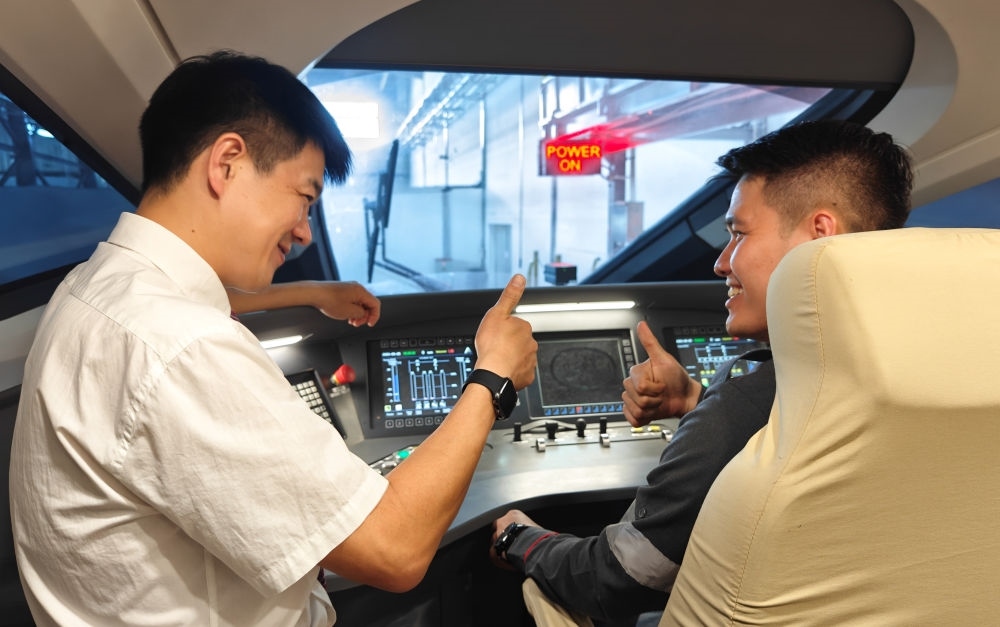 2023年8月25日，在印度尼西亞萬隆的雅萬高鐵德卡魯爾動(dòng)車所內(nèi)，中國師傅穆振（左）向印尼火車司機(jī)塞蒂亞萬講解動(dòng)車組出庫前的上電作業(yè)。新華社記者 徐欽 攝