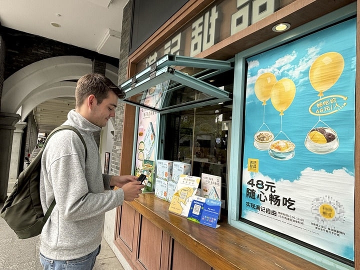 來自德國的留學(xué)生理查德在杭州西湖邊一家商鋪使用支付寶掃碼支付（2024年4月11日攝）。新華社發(fā)