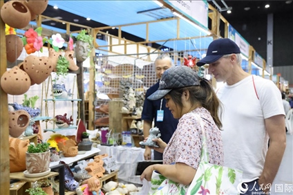游客在蘭納博覽會特色展位上選購工藝品。人民網(wǎng)記者楊一攝