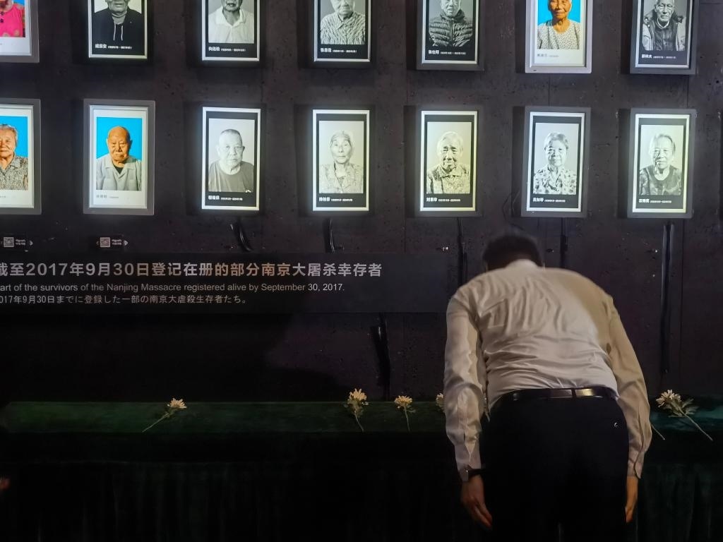 7月18日，人們向離世的南京大屠殺幸存者獻(xiàn)花、鞠躬。新華社記者邱冰清 攝