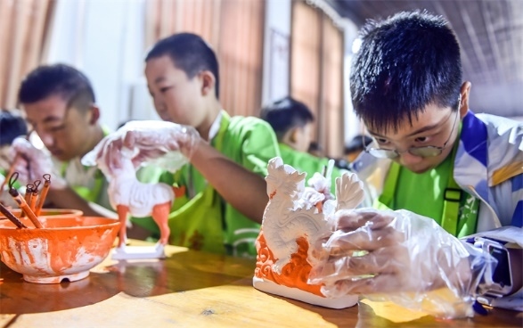 小朋友們在洛陽市孟津區(qū)朝陽鎮(zhèn)南石山村體驗唐三彩素胎施釉技藝。圖片來源：視覺中國