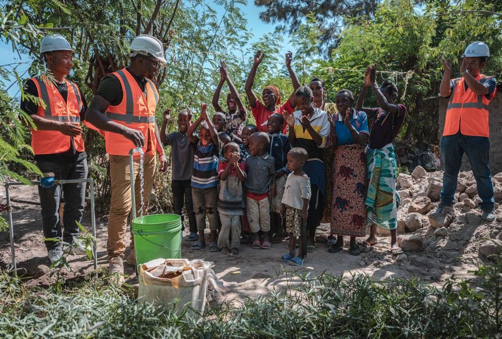 2023年6月13日，在坦桑尼亞姆萬扎省米松圭，工作人員接通水管后贏得當(dāng)?shù)鼐用窆恼茪g呼。新華社記者 王冠森 攝