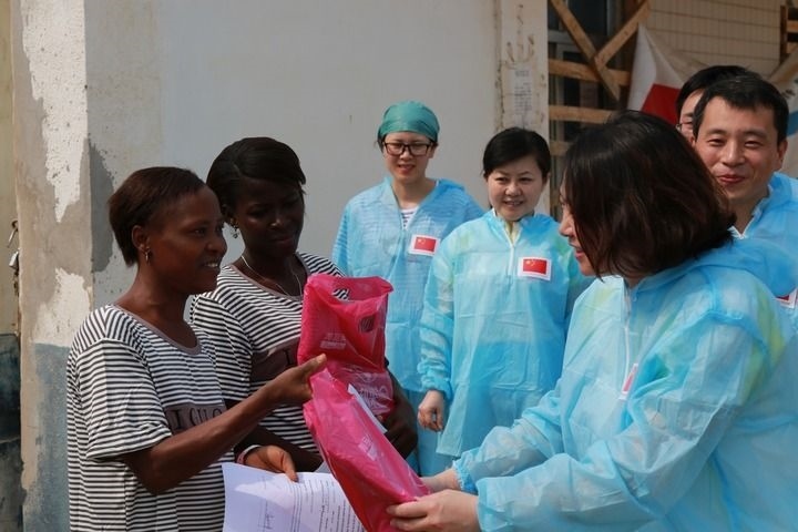 2015年4月4日，在位于塞拉利昂首都弗里敦市郊的中塞友好醫(yī)院埃博拉診療中心，中國(guó)第四批援塞醫(yī)療隊(duì)副隊(duì)長(zhǎng)邵蔚（右前）向被治愈的埃博拉出血熱患者贈(zèng)送禮物。新華社發(fā)（祖榮強(qiáng) 攝）