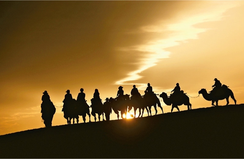 新時代以來，文化和旅游深度融合發(fā)展體制機制不斷健全，成功走出了一條獨具特色的中國旅游發(fā)展之路。圖為2024年9月1日清晨，游客在甘肅省敦煌市鳴沙山月牙泉景區(qū)乘騎駱駝，欣賞大漠風(fēng)光，體驗絲路風(fēng)情。 新華社發(fā) 張曉亮/攝