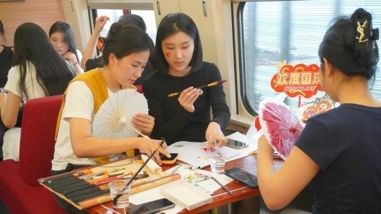 10月1日，旅客們?cè)贕1634次列車上給油紙傘作畫。新華社記者周義 攝