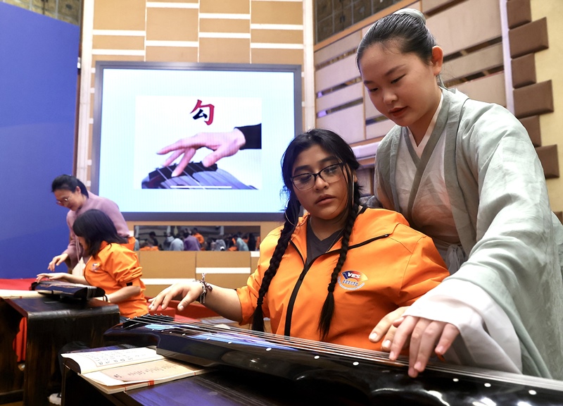 2024年3月20日，美國華盛頓州中學(xué)生代表團(tuán)北京大學(xué)交流活動在北京大學(xué)英杰交流中心舉行。圖為來自華盛頓州的中學(xué)生體驗(yàn)古琴。