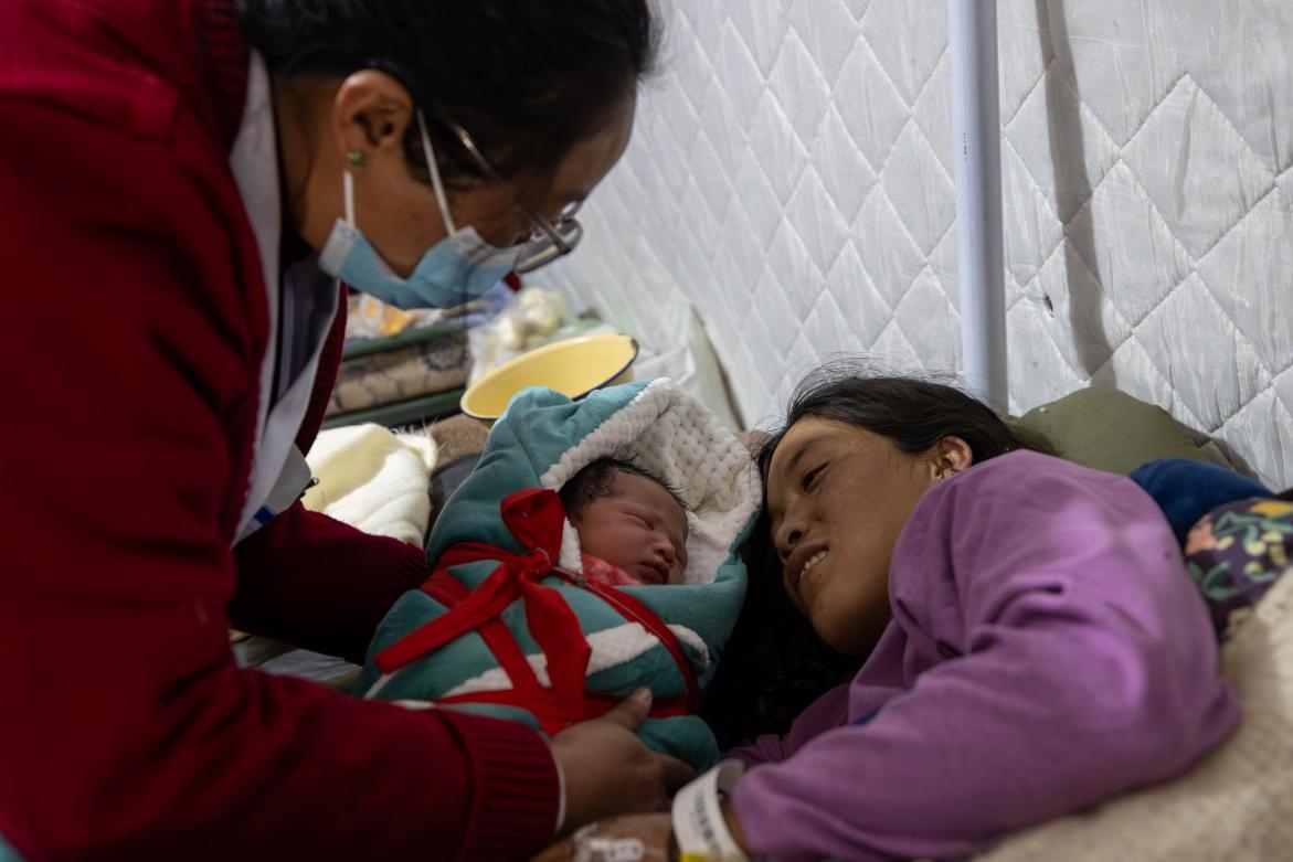 1月10日，定日縣中心醫(yī)院的婦產(chǎn)科醫(yī)生悉心照看一位母親和她懷里的新生兒。人民日?qǐng)?bào)記者張武軍攝