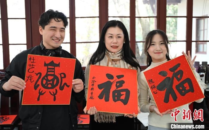 1月20日，外籍留學(xué)生和西泠印社社員李硯(中)展示各自創(chuàng)作的福貼。當(dāng)日，來自巴西、馬來西亞、加納、哈薩克斯坦的外籍留學(xué)生在浙江杭州西泠印社體驗福貼、春聯(lián)和篆刻，感受古老的中國傳統(tǒng)文化。中新社記者 王剛 攝