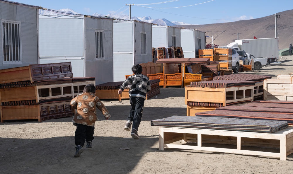 2025年1月13日，在定日縣嘎旦村，兩個孩子在剛運來的兩排藏床間奔跑。新華社記者丁增尼達 攝