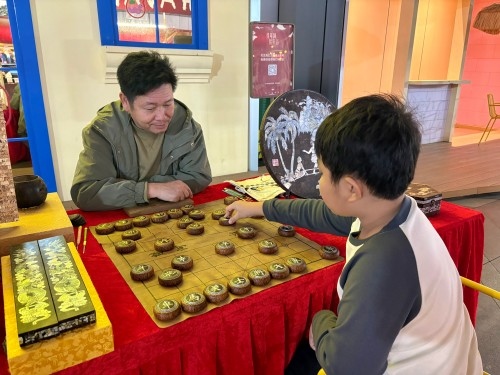 柯秋楓與市民下椰雕象棋。人民網(wǎng) 陳葉欣攝