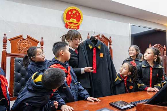 圖②：干警向同學(xué)們介紹法袍。