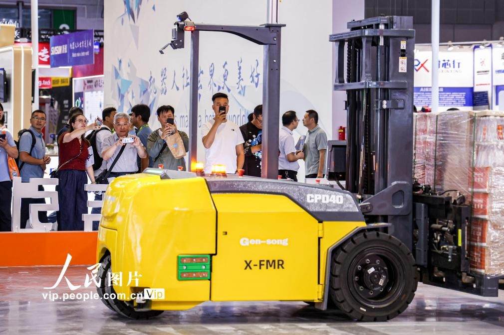 第24屆中國工博會現(xiàn)場，觀眾觀看叉取機(jī)器人作業(yè)演示。王初攝（人民圖片網(wǎng)）