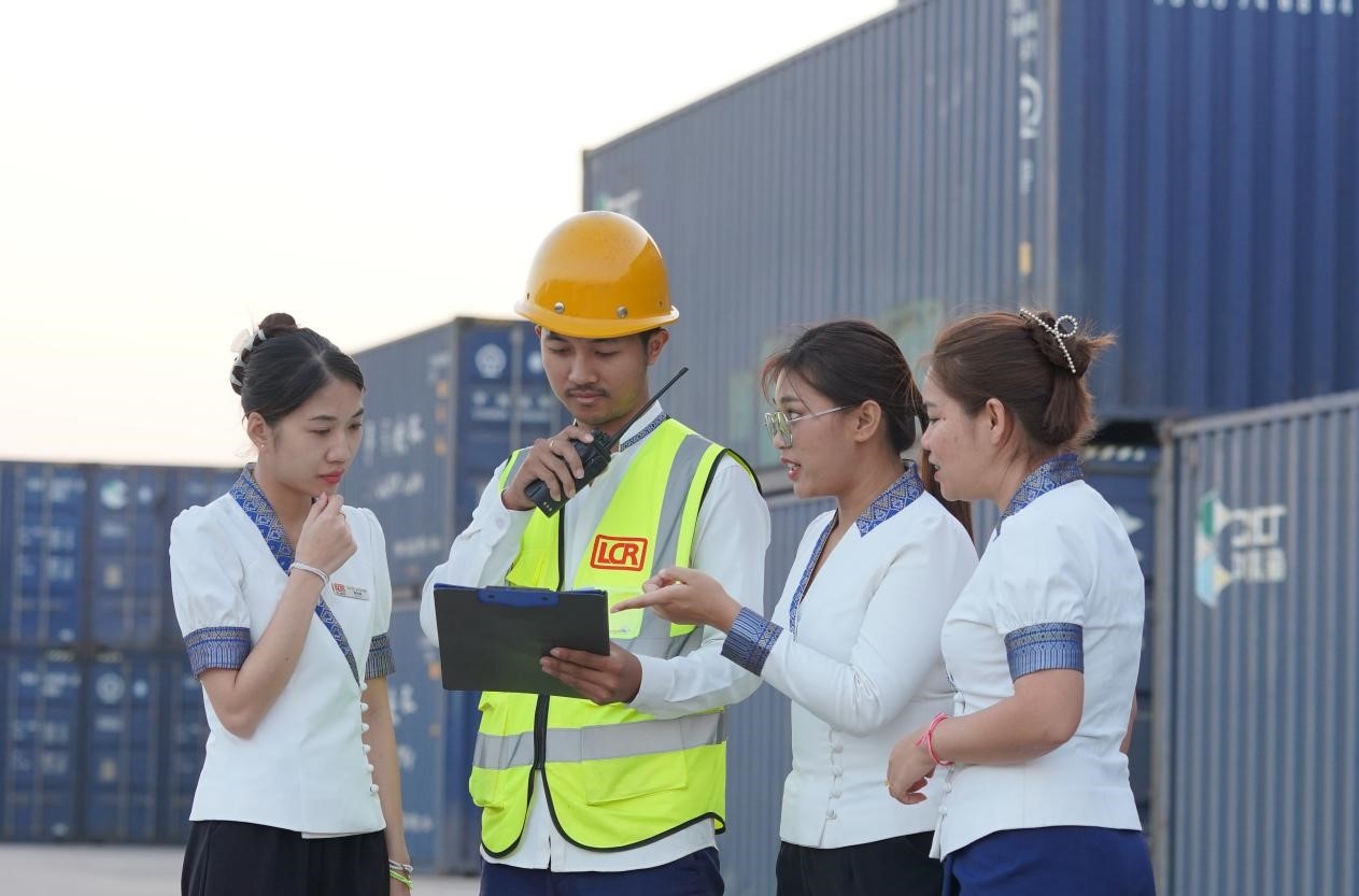 萬象南站貨運(yùn)值班員陳尼啦（左一）與同事在一起討論工作。老中鐵路有限公司供圖