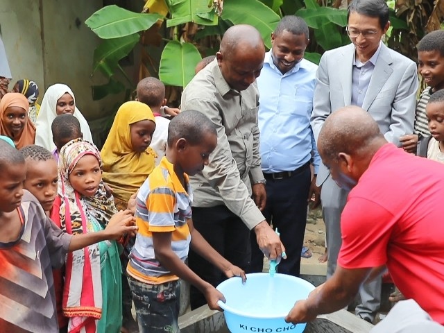 在日前舉行的安全供水工程揭牌儀式上，當?shù)匦∨笥言诠┧c接水。 施亮攝