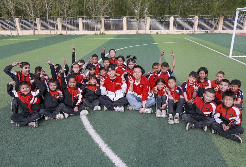 4月23日，在新疆克州阿圖什市哈拉峻鄉(xiāng)謝依特小學，支教教師王俊文（中左）、李軻凡（中右）和學生在一起。