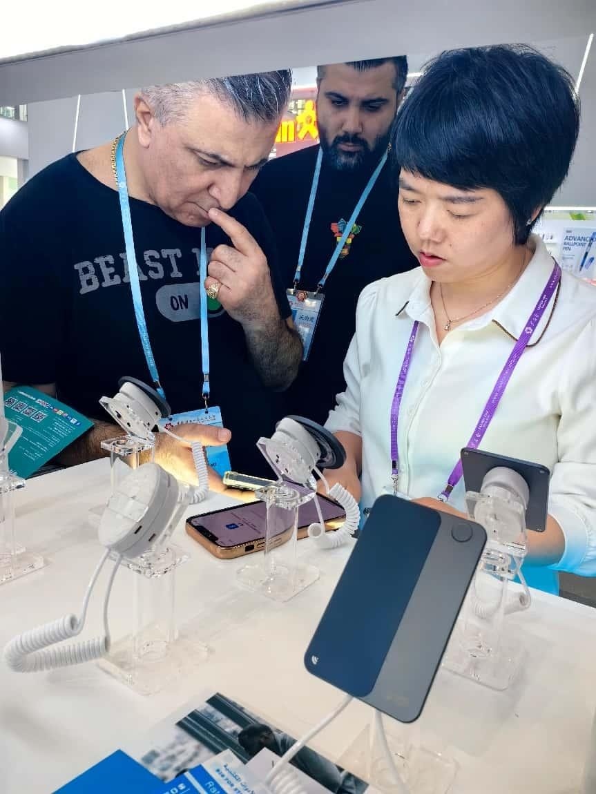 展臺工作人員向外商展示“AI TOP翻譯終端”。圖片來源：受訪者提供